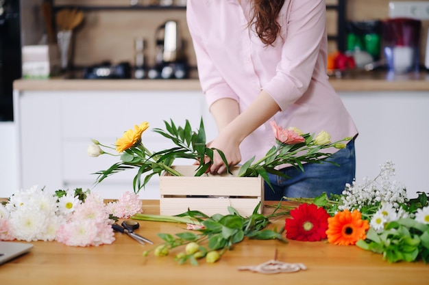 Bloemist op het werk jonge brunette vrouw handen maken mode moderne compositie van verschillende bloemen thuis