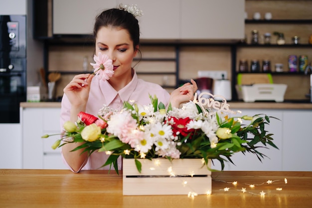 Bloemist op het werk mooie jonge brunette vrouw die mode moderne compositie maakt van verschillende bloemen die thuis decoreren met led-verlichting