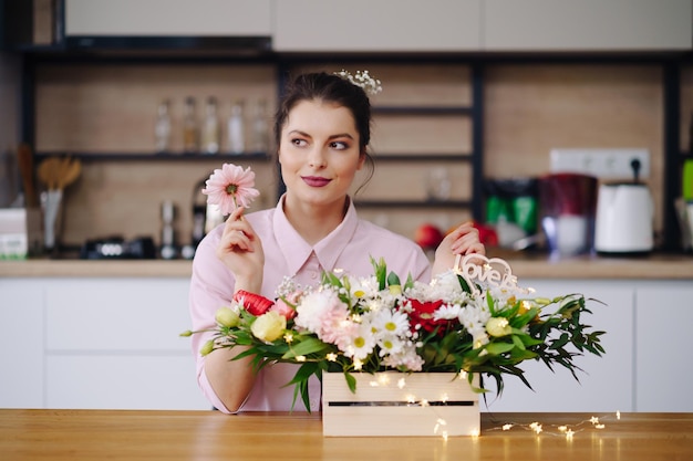 Bloemist op het werk mooie jonge brunette vrouw die mode moderne compositie maakt van verschillende bloemen die thuis decoreren met led-verlichting