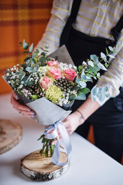 Bloemisthanden die boeket van de lentebloemen tonen.