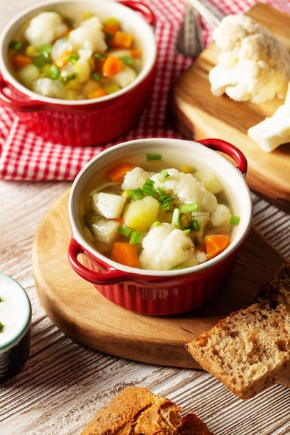 Bloemkool vegetarische soep in pan, brood, rauwe bloemkool