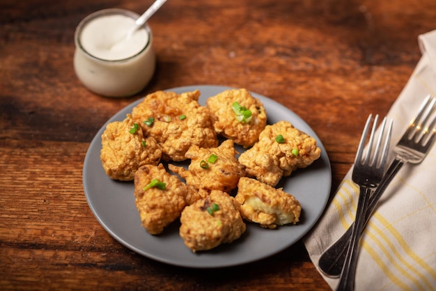 Bloemkoolvleugels eten Stukjes bloemkool met veganistische sauzen op een bord Houten achtergrond Vegetarisch eten