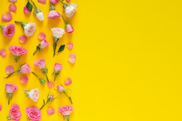 Bloemmotief gemaakt van roze en beige rozen, groene bladeren op gele achtergrond. valentijnsdag achtergrond. plat lag, bovenaanzicht.