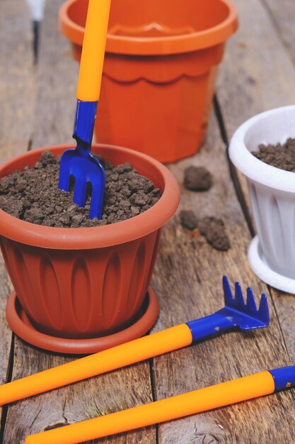 Bloempotten en set decoratieve tuingereedschap schop hark en hooivork op een houten achtergrond