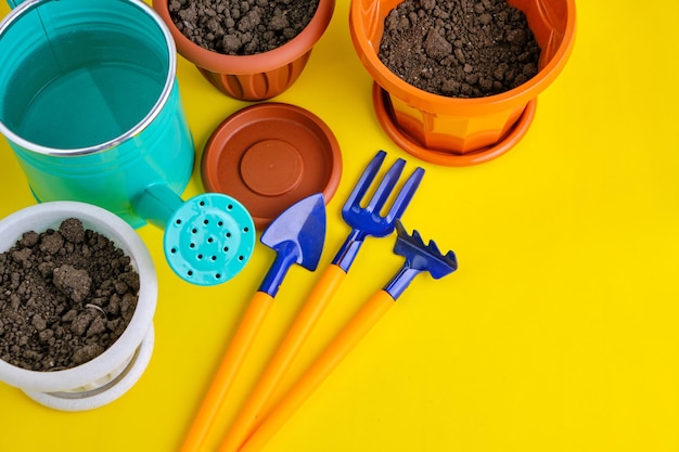 Bloempotten gieter en tuingereedschap felgele achtergrond