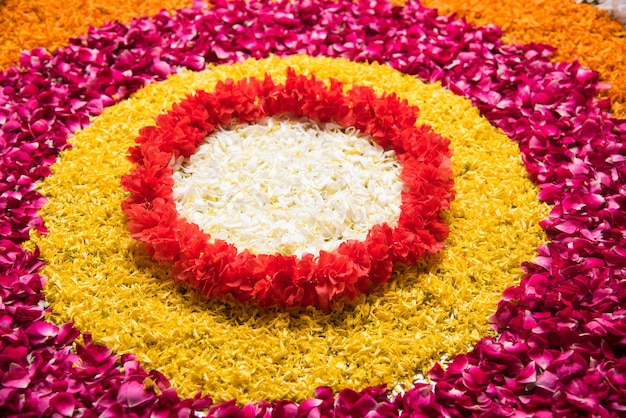 Bloemrangoli voor Diwali of Pongal of een hindoe-festival met goudsbloem of zendu-bloemen en rode rozenblaadjes, selectieve focus