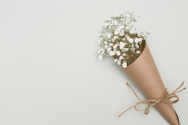 Bloemstuk witte bloemen in ambachtelijke verpakking op een gestructureerde achtergrond