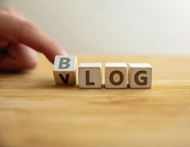 Blog vs vlog concept finger flips letter at wooden cube changing the word blog text to vlog video