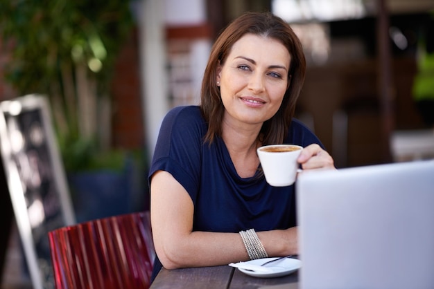 Bloggen in de coffeeshop Shot van een aantrekkelijke vrouw die haar laptop gebruikt in een coffeeshop