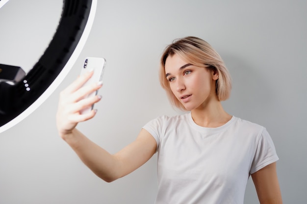 blogger girl is broadcasting live via a smartphone under a ring lamp