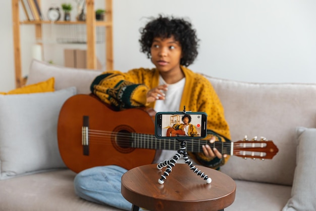 Blogger guitarist african american girl blogger playing guitar talking to webcam recording vlog