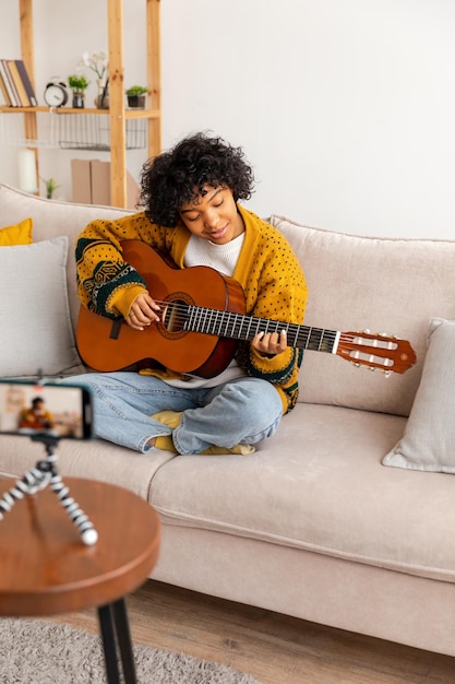 ブロガー ギタリスト 幸せなアフリカ系アメリカ人の女の子のブロガーがギターを弾いて歌う歌の録音 vlog soc