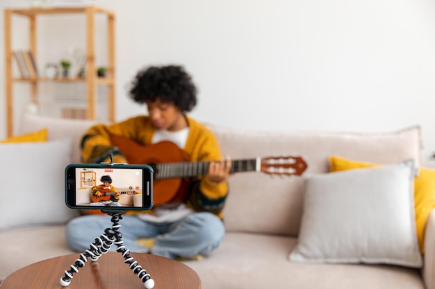 ブロガー ギタリスト 幸せなアフリカ系アメリカ人の女の子のブロガーがギターを弾いて歌う歌の録音 vlog soc