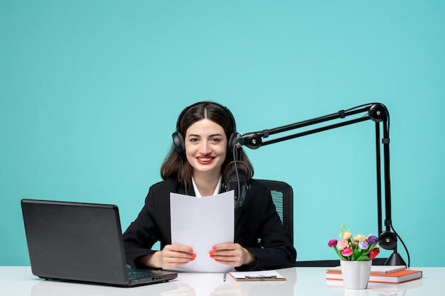 Blogger journalist lovely young girl in black blazer recording speech on camera holding papers