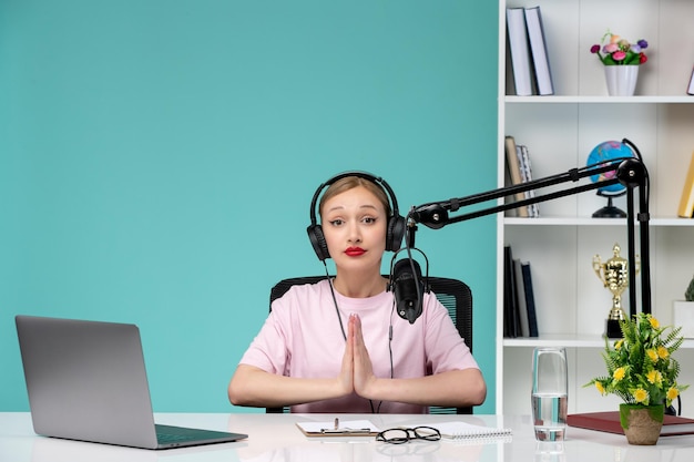 Blogger journalist pretty cute blonde girl recording video on computer praying