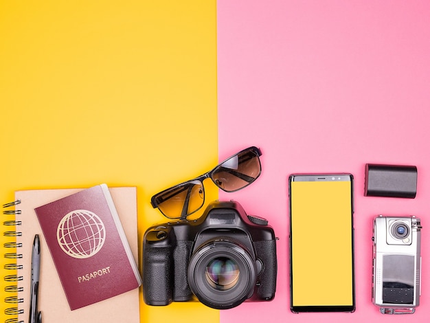 Blogger klaar voor reizen en zomervakantie. Bovenaanzicht. Plat leggen. DSLR en actiecamera, zonnebril, smartphone en paspoort op twee gekleurde achtergrond. Pastelkleuren