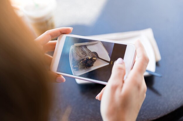 Blogger neemt foto van dessert op smartphone in café