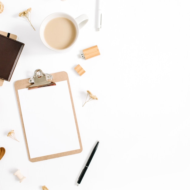 Blogger of freelancer werkruimte met klembord, koffiemok, notebook en accessoires op witte achtergrond. Platliggend, bovenaanzicht minimalistisch bruin gestileerd thuisbureau. Schoonheid blogconcept.