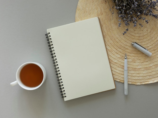 Blogger's desk mockup. Dry flowers, opened notebook with copy space over straw plate. Copy space.