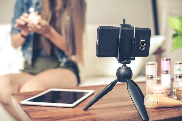 Blogger van blanke vrouw met beoordelingsproduct en pratende camera live video opnemen op sociaal netwerk thuis. Online verkopers die cosmetica verkopen op sociale media via mobiele telefoons.