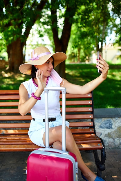 Blogger woman in straw hat and removed mask holds on her head