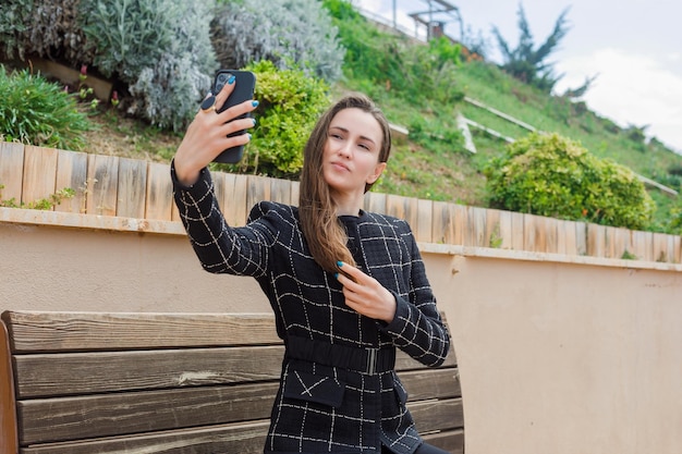 Bloggermeisje neemt selfie met haar smartphone door haar in het park te houden