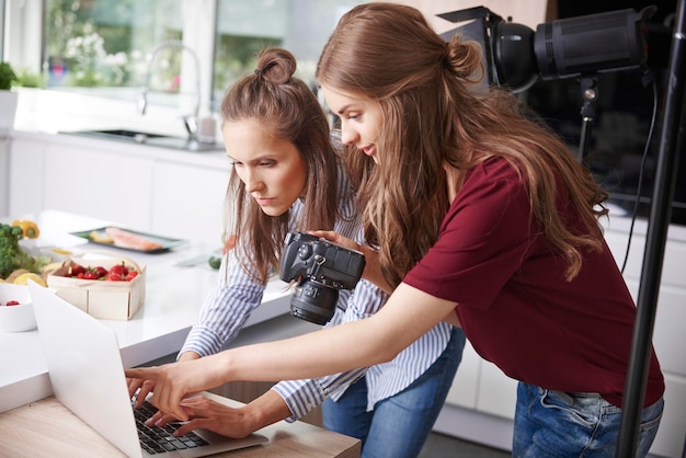 Bloggers using laptop and camera in kitchen