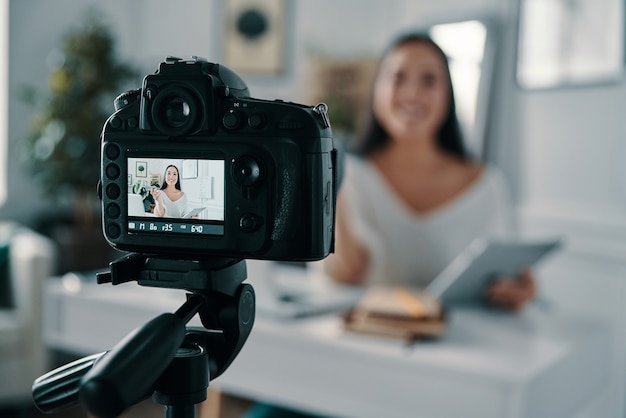 Foto il blog è la sua vita. bella giovane donna che gesticola e sorride mentre realizza un nuovo video per il suo blog