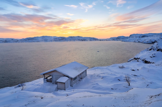 Blokhuis en de Barentsz Zee bij zonsondergang in Teriberka, Moermansk, Kola Peninsula. Rusland