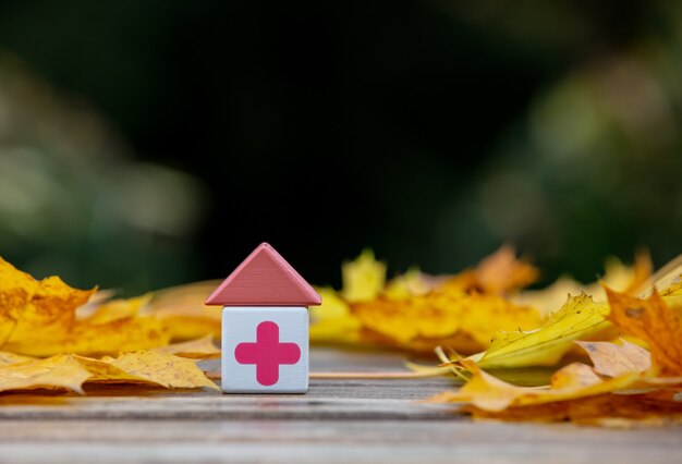 Blokken met medisch rood kruis naast bladeren op een houten tafel