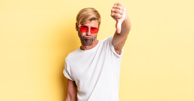 Blond adult man feeling cross,showing thumbs down and wearing sunglasses