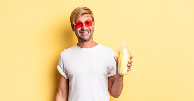 Blond adult man looking happy and pleasantly surprised with a milkshake