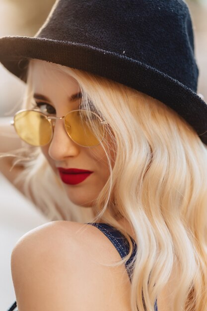 Photo blond attractive girl in sunglasses and stylish hat at summer sunshine urban