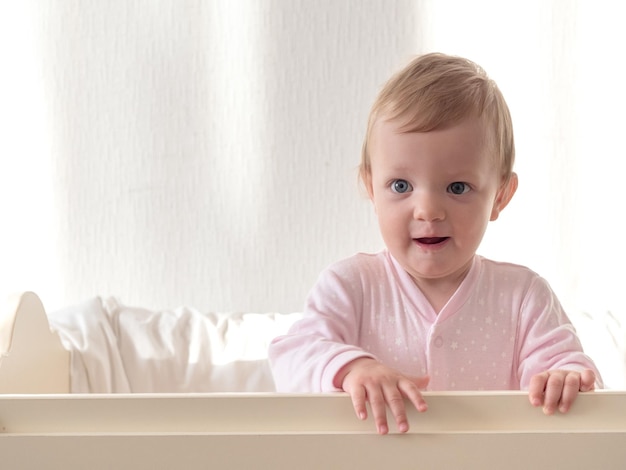 Blond baby in crib looking