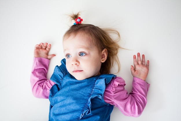 The blond baby girl with hands up on white