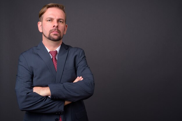 Blond bearded businessman with goatee against gray wall