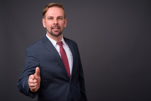 Blond bearded businessman with goatee against gray wall