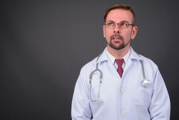 Blond bearded doctor with goatee against gray wall