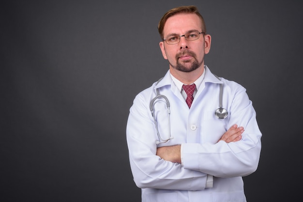 Blond bearded doctor with goatee against gray wall