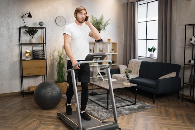 Blond bearded male in white tshirt jogging on treadmill