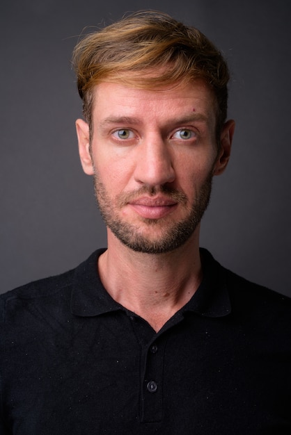 Blond bearded man against gray wall