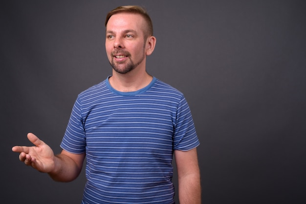 Blond bearded man with goatee against gray wall