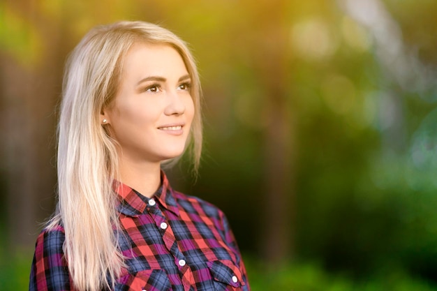 Blond beautiful girl smiles in the park