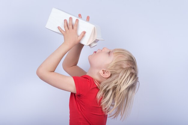 カートンから牛乳を飲む金髪の少年