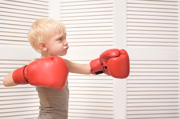 Blond boy in red boxing gloves. 