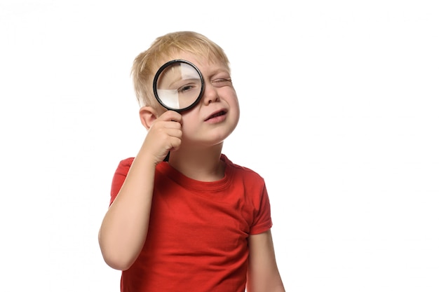 Photo blond boy with a magnifying glass in his hands