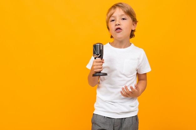 Ragazzo biondo con un microfono su una parete arancione dello studio