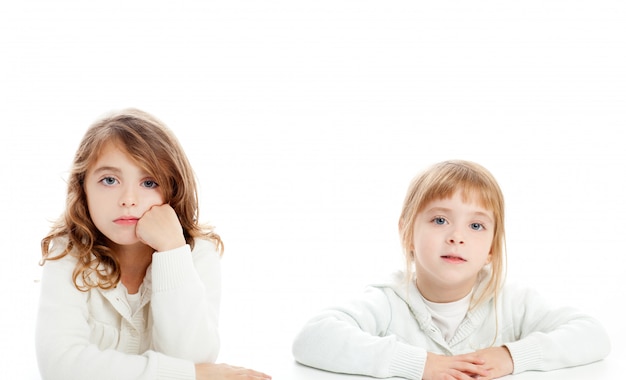 Ritratto delle ragazze del bambino biondo e castana su bianco