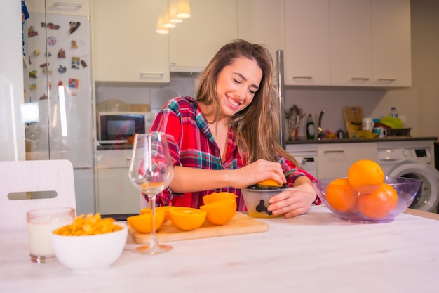 Bionda donna caucasica con un succo d'arancia fresco per la colazione nella sua cucina