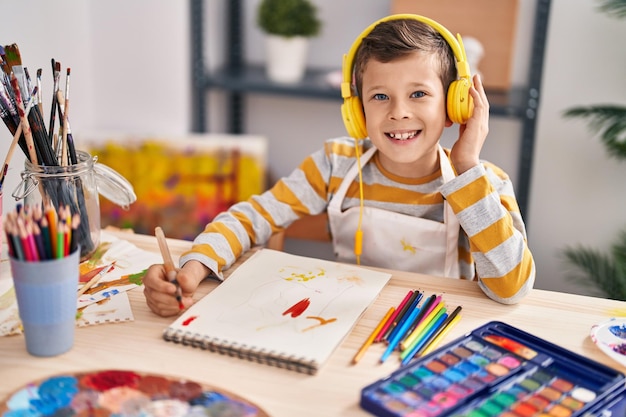 Blond child listening to music drawing at art studio